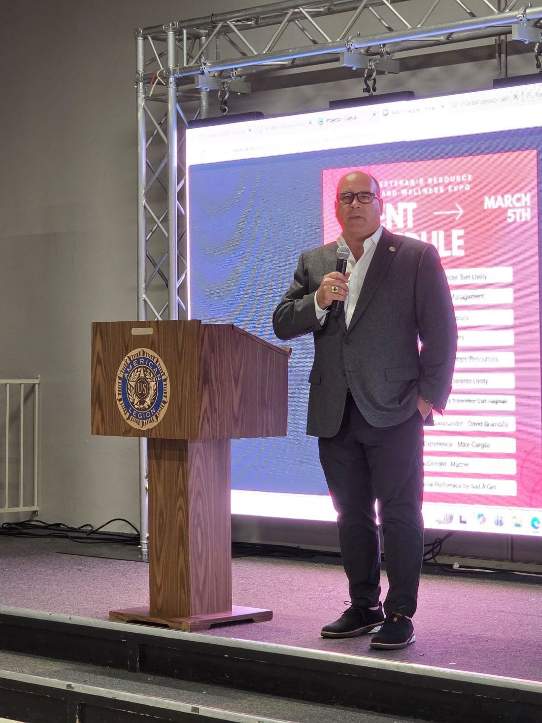 Supervisor Curt Hagman standing on stage, speaking into a microphone at the 2026 Veterans Resource and Wellness Expo.