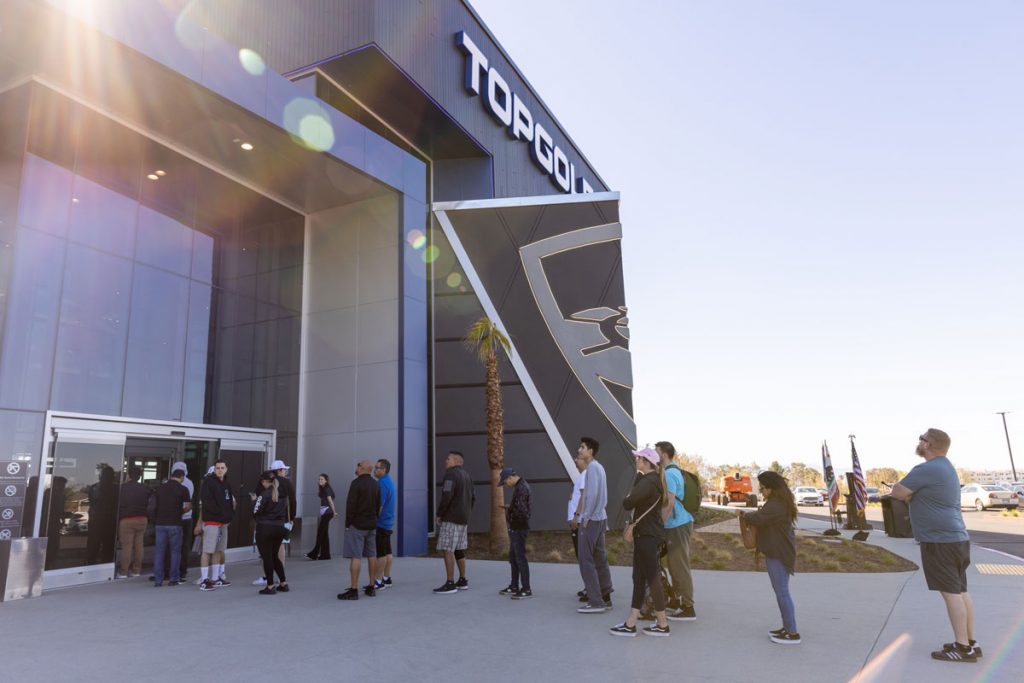 Entrance of Topgolf with a line of customer waiting to enter.