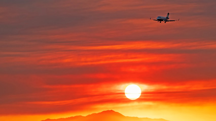 Plane flying at sunset with mountains below