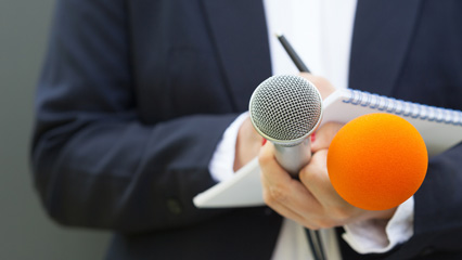 business professional holding microphones and notepad