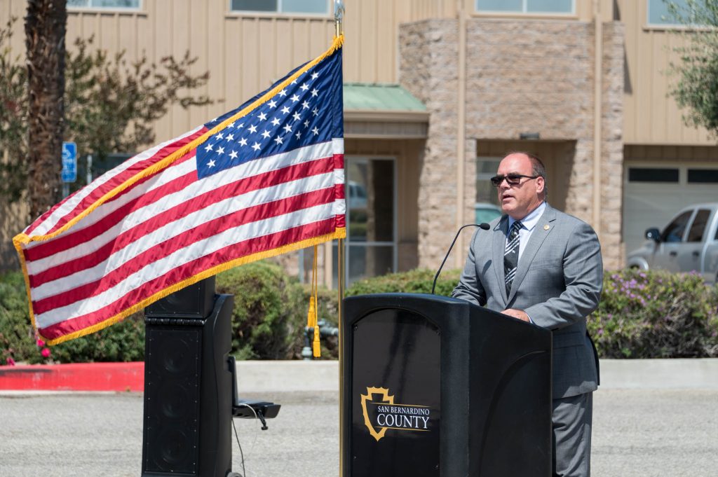 Supervisor Hagman speaking at a podium next to an American flag