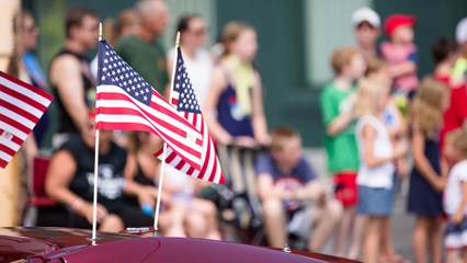 American flags on a car in front of a crowd of people