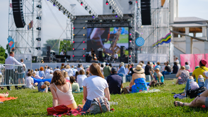 People sitting on the lawn watching a concert