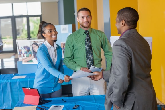 Man handing resume to a man and a woman