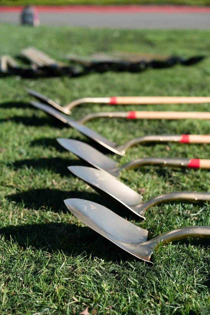 A row of shovels laying on the grass