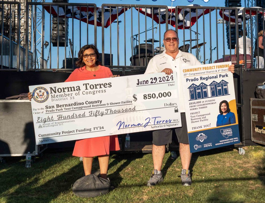 Congresswoman Norma Torres holding a check in the amount of $850,000 for Prado Park and Supervisor Curt Hagman holding a sign about the Community Project Funding for Prado Regional Park.