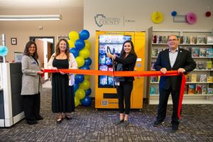 Officials cut ribbon to celebrate new book vending machine at county library.