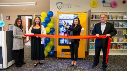 Officials cut ribbon to celebrate new book vending machine at county library.