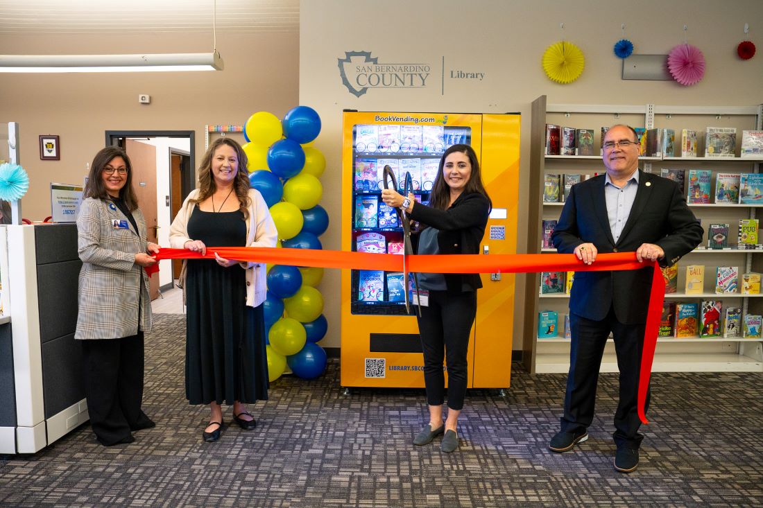 Officials cut ribbon to celebrate new book vending machine at county library.