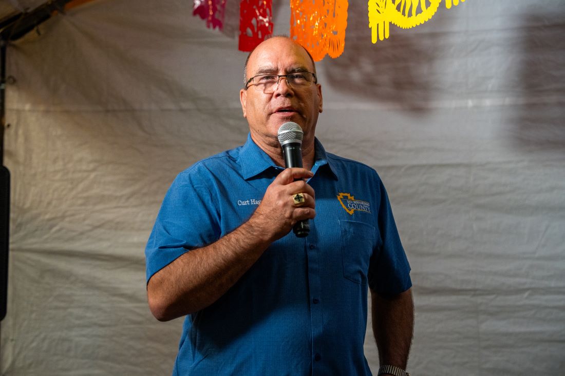 Supervisor Hagman wearing a blue button down shirt speaking into the microphone at the Let's Taco 'Bout It Upland event.