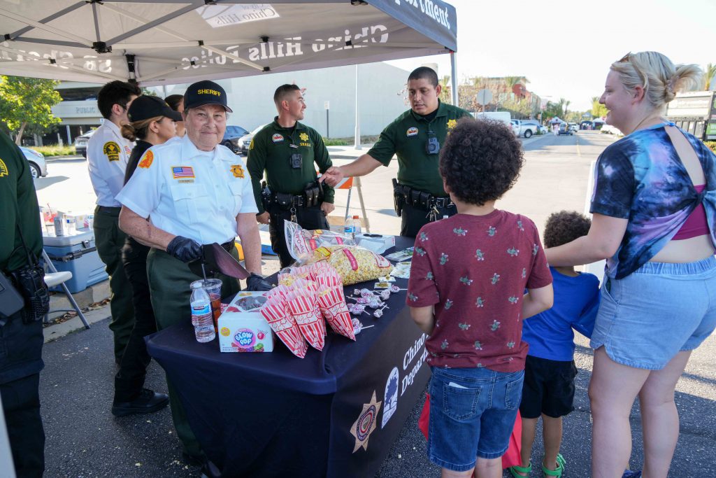Chino Hills Sheriff's Department staff hand out snacks and chat with families at a community event.