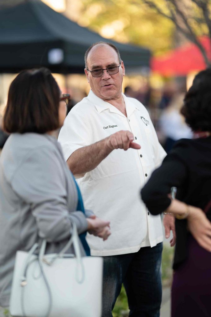 Curt Hagman points while speaking with two women at an outdoor Summer Open House event.
