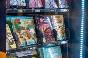 Children’s books displayed inside a vending machine, including Xavier Riddle and Carmen Sandiego.