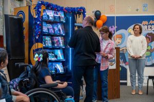 Supervisor Curt Hagman demonstrates the new book vending machine with students and school staff watching.