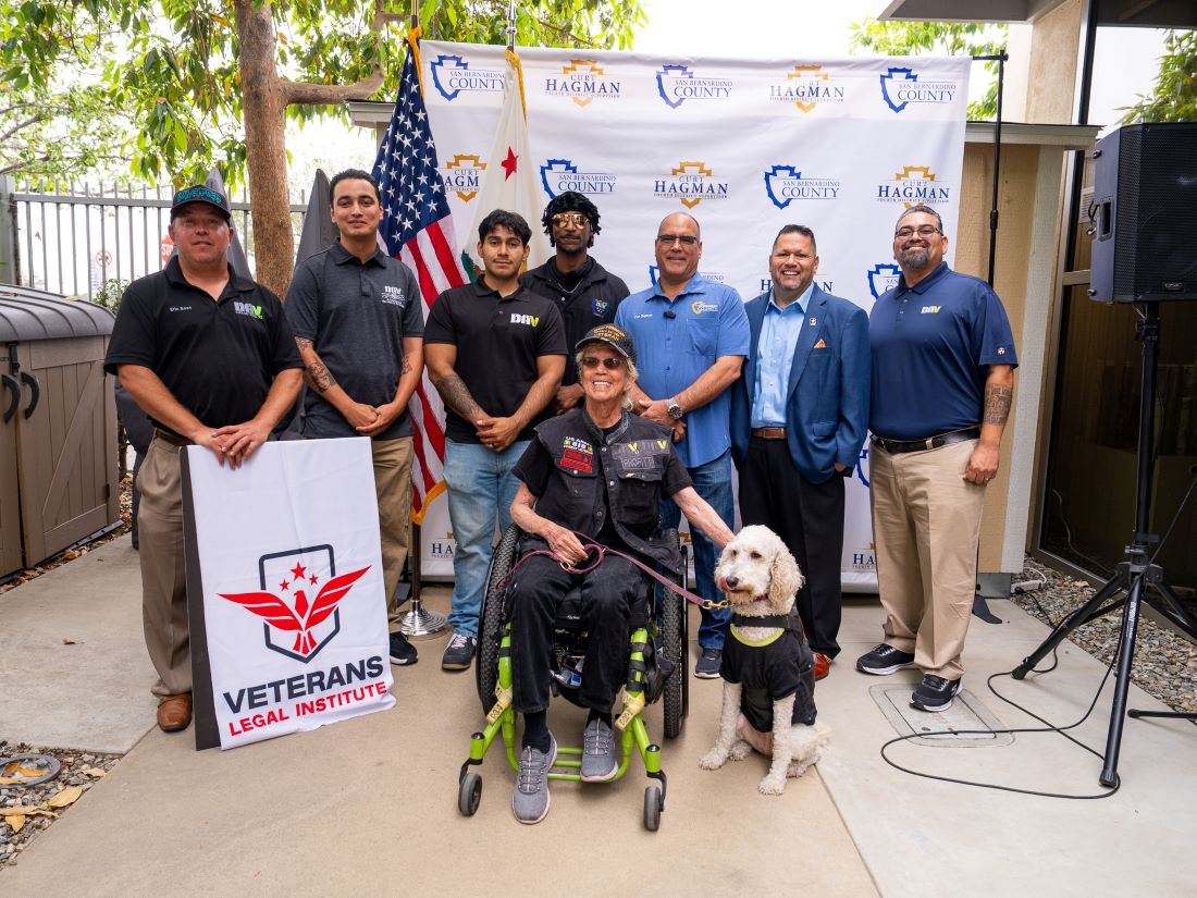 Veterans, supporters, and a service dog gather with Supervisor Hagman at a Veterans Legal Institute event.