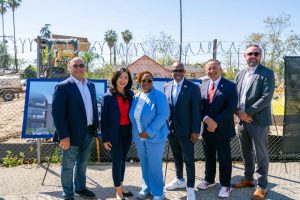 Officials and partners pose at construction site for U.S. Vets veterans housing groundbreaking.