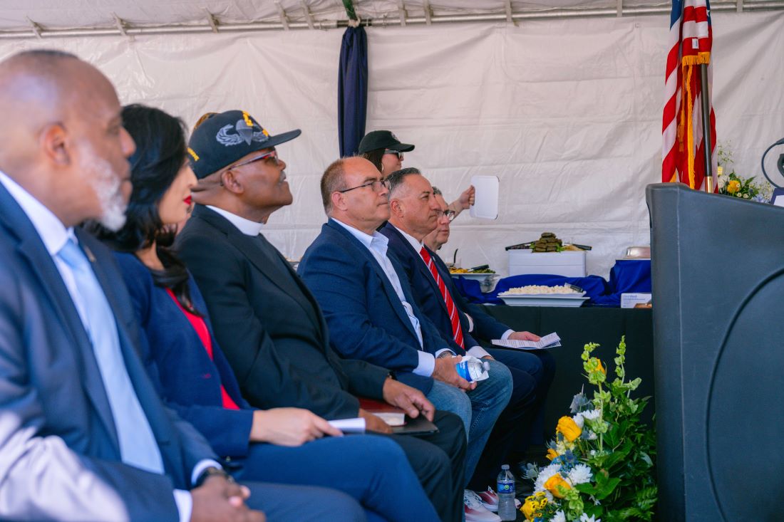 Officials seated under a tent listening during U.S. Vets Inland Empire veterans housing groundbreaking.