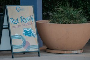 Sign for San Bernardino County's Reel Reality Fentanyl Film Contest next to a large planter.