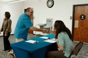 Supervisor Curt Hagman greets a community member at a check-in table at the end of the 2025 Summer Reading Program.