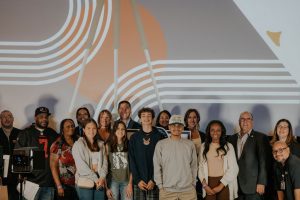 Group photo of students and adults at a fentanyl film contest event with a screen backdrop.