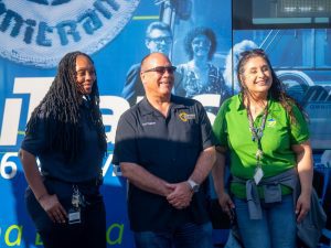 Supervisor Hagman poses with Omnitrans staff in front of a transit bus at the community event.