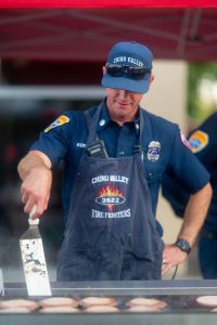 Chino Valley firefighter grills burgers for guests during the Fourth District Summer Open House.