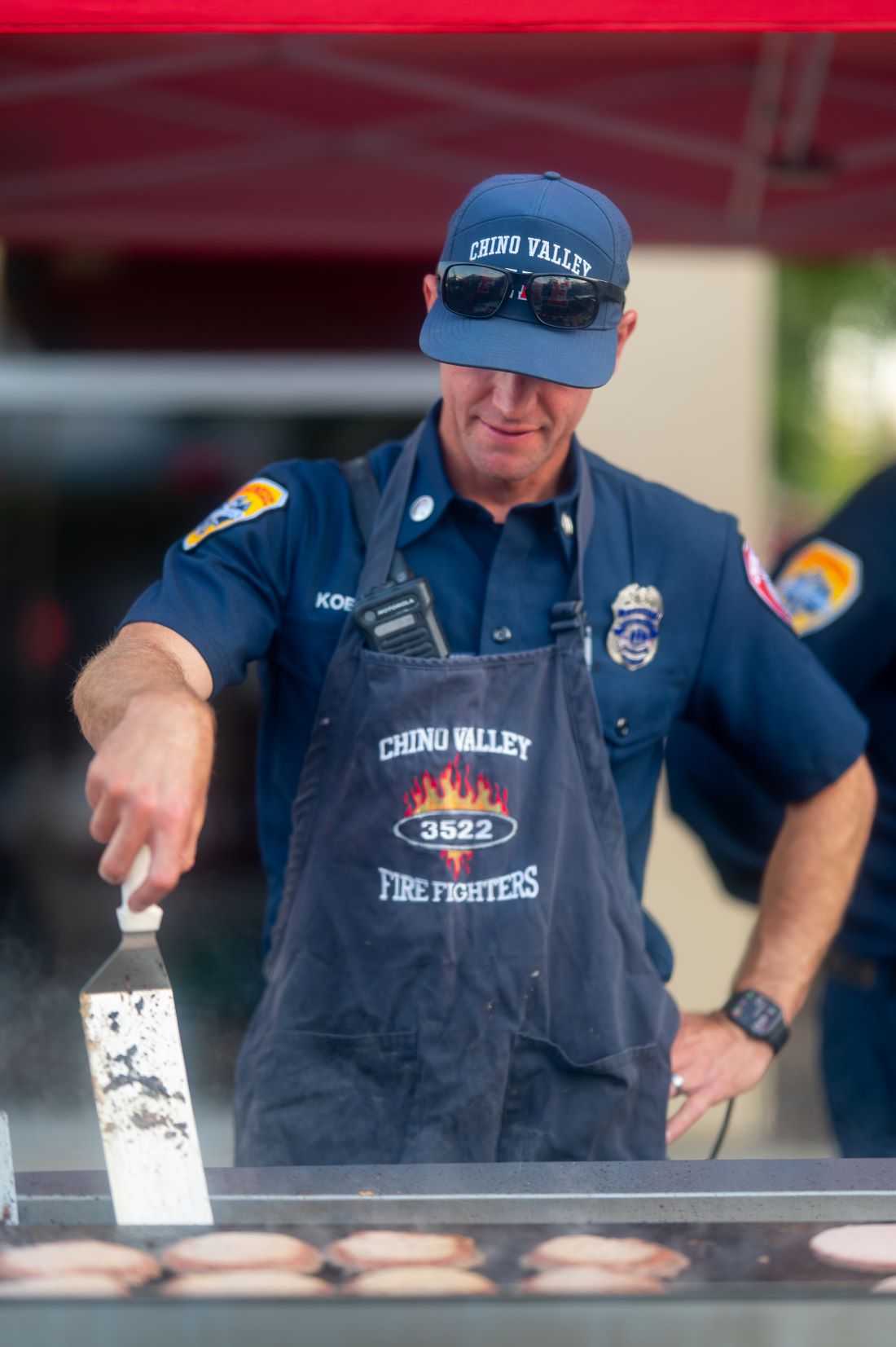 Chino Valley firefighter grills burgers for guests during the Fourth District Summer Open House.