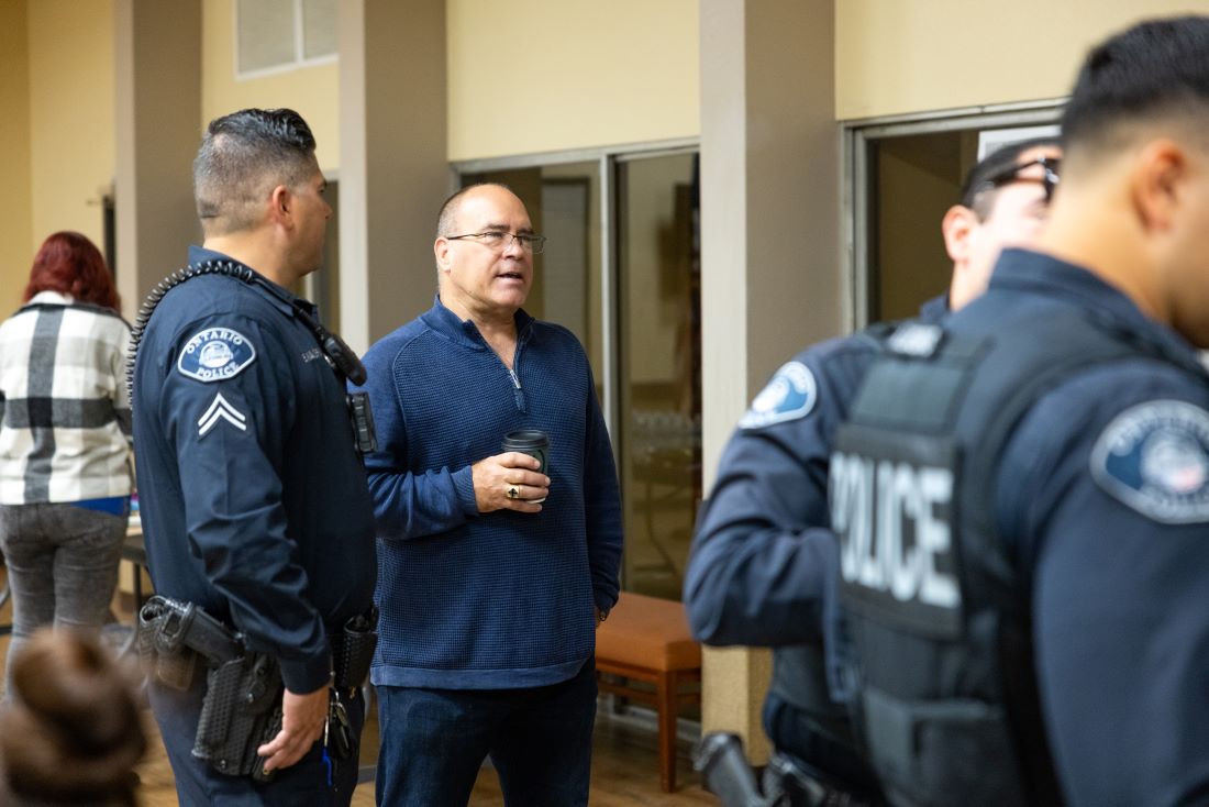 Supervisor Curt Hagman speaks with Ontario Police Officers inside a community center.