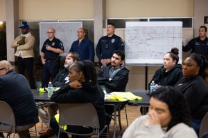 Community members and police officers attend an indoor briefing during the 2026 Point-In-Time Count