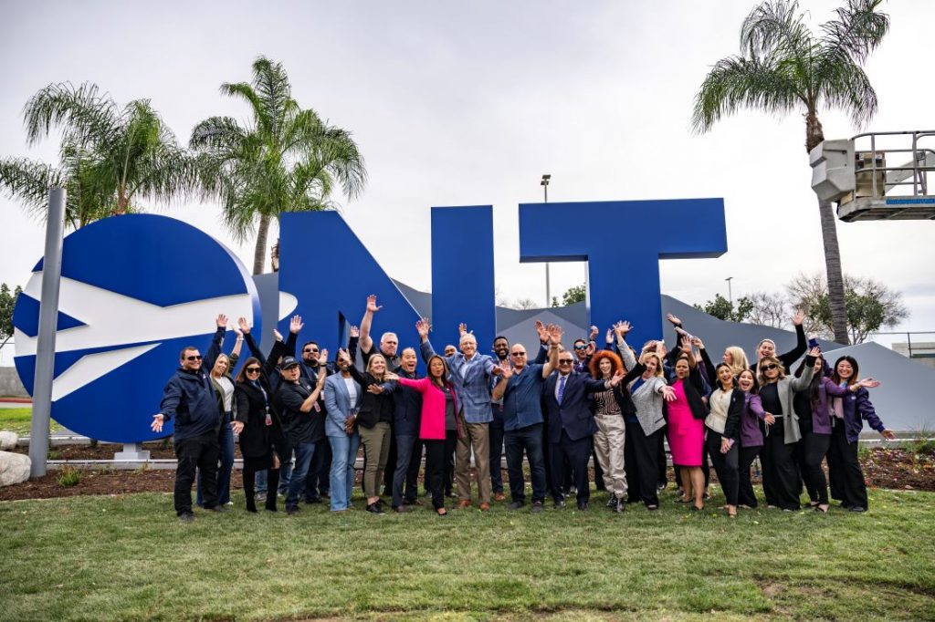 Community leaders and partners pose in front of the ONT monument sign.