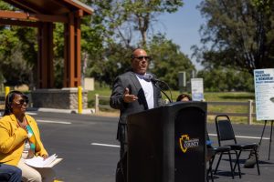 Supervisor Hagman speaking at a podium with the San Bernardino County seal during the Prado Regional Park improvements ribbon-cutting ceremony.