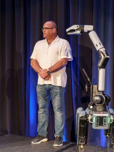 Supervisor Curt Hagman stands on stage beside a robotic demonstration at the City-County Conference.