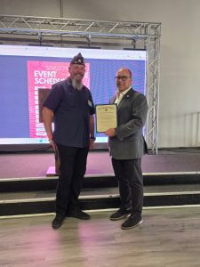 A male presents Supervisor Hagman with a certificate thanking him for his contribution to the American Legion.